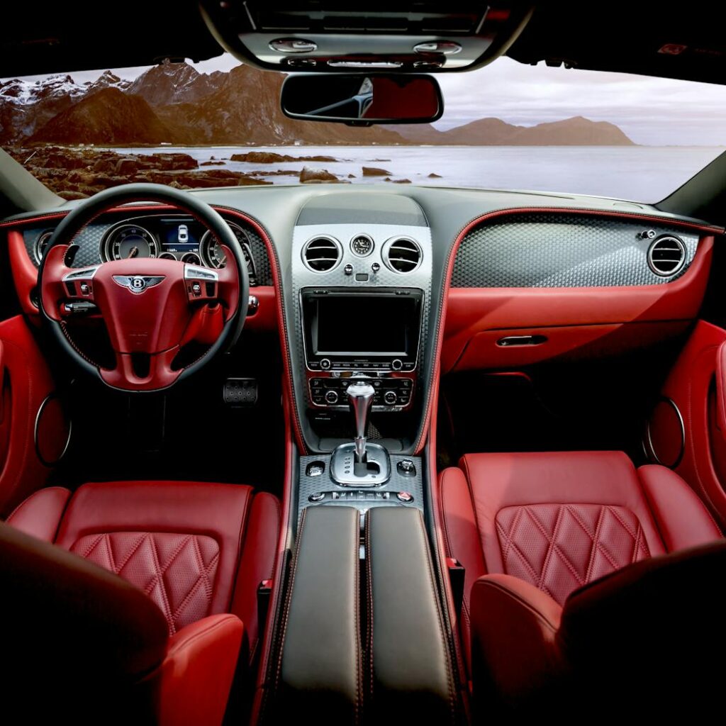 Photo by Pixabay Red leather luxury sports car interior with mountain backdrop outside the window.