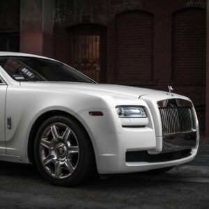 Elegant white Rolls Royce Ghost parked in a stylish urban backdrop, showcasing luxury and design.