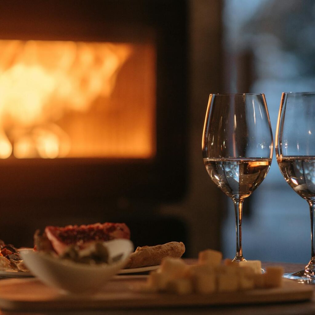 Intimate dining by the fireplace with wine and appetizers, perfect for a cozy winter evening.