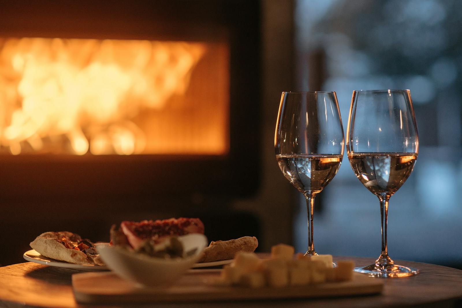 Intimate dining by the fireplace with wine and appetizers, perfect for a cozy winter evening.