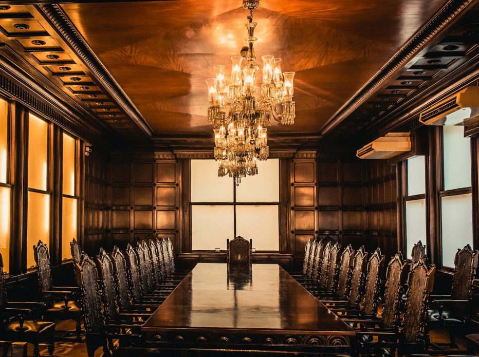 Luxury dining room featuring a grand chandelier, wooden table, and ornate chairs.